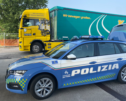 Italienisches Polizeiauto mit der Aufschrift Polizia steht vor einem LKW.
