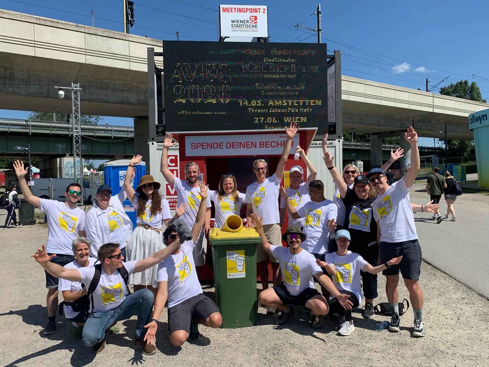Eine Gruppe Menschen steht am Festivalgelände vor einem Holzstand für die Rückgabe von Bechern.