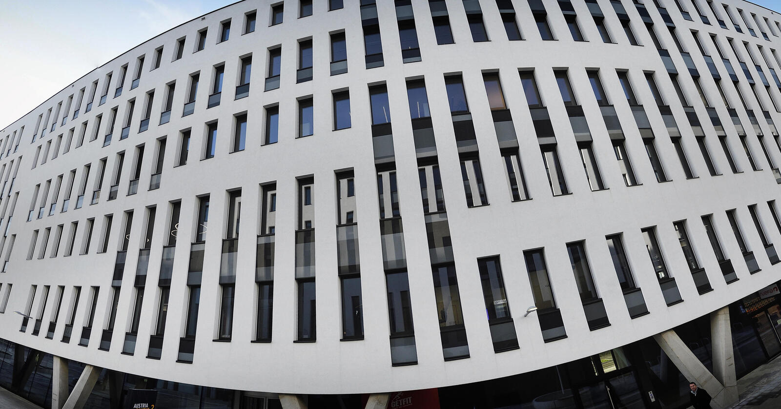 Weißes Bürogebäude mit hohen dunklen Fenstern.