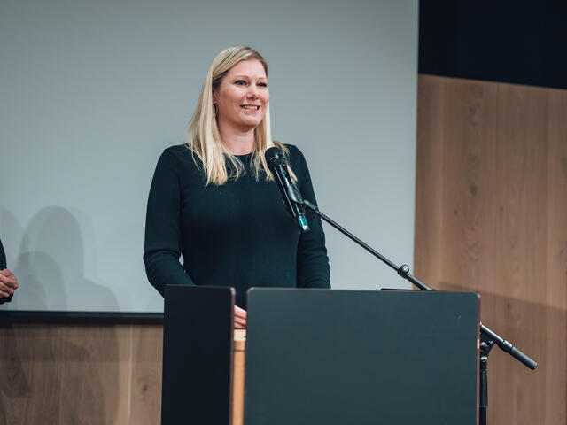Melanie Graf spricht an einem Rednerpult.