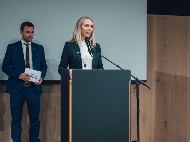 Katja Ulbricht spricht in ein Mikrophon an einem Pult.