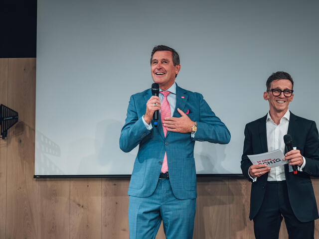 Bundesminister Peter Hanke spricht auf der Bühne, er und Moderator Stephanos Berger lachen.
