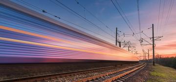 Zug fährt durch ländliche Gegend in den Sonnenuntergang.