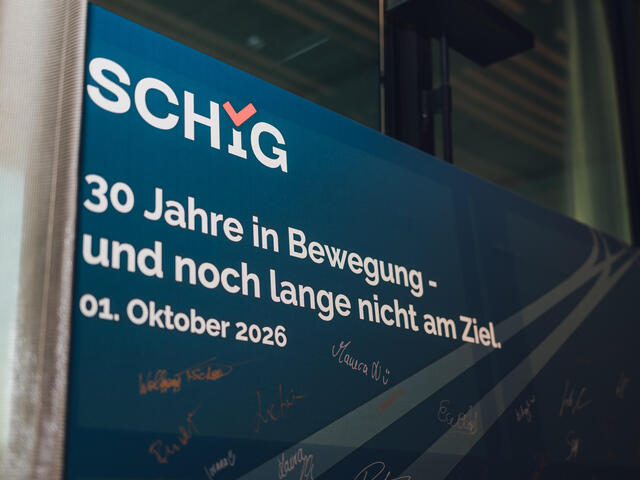Leinwand mit SCHIG Logo und Slogan: 30 Jahre in Bewegung - und noch lange nicht am Ziel. 01. Oktober 2026