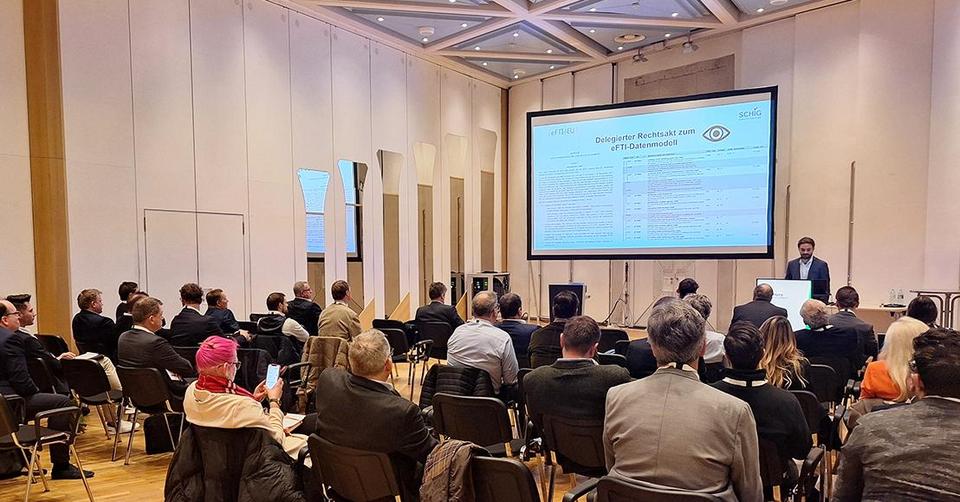 eFTI4EU wird im Festsaal mit einer Präsentation durch einen Sprecher vor Publikum vorgestellt.