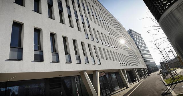 Weißes Bürogebäude mit hohen schwarzen Fenstern.