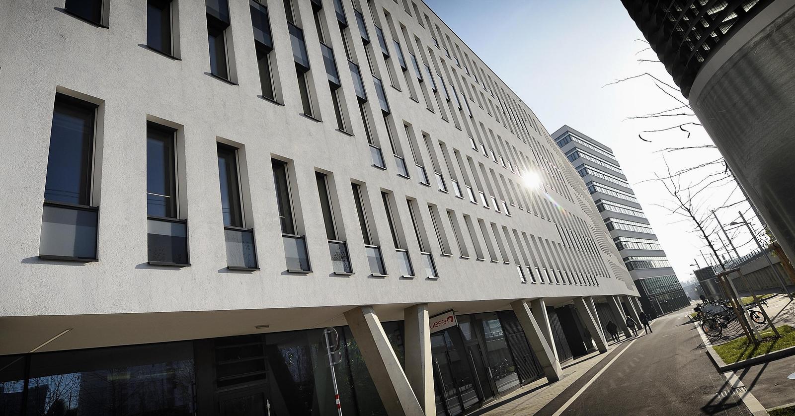 Weißes Bürogebäude mit hohen schwarzen Fenstern.